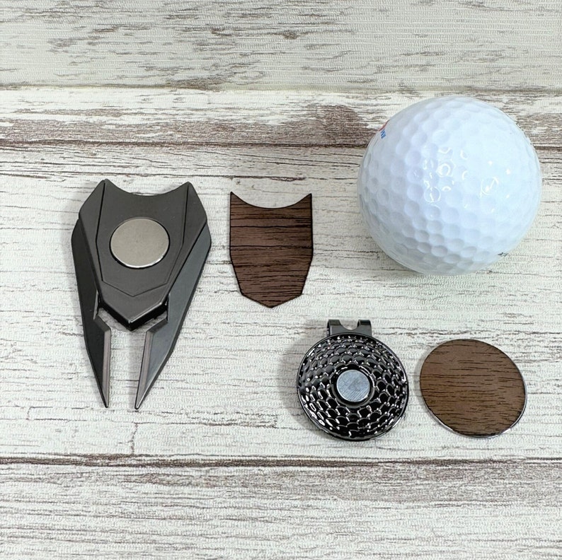 Pu&ograve; includere: Un set di accessori per il golf che include un segnalibro magnetico per la palla, una palla da golf, uno strumento per riparare i divot, un fermaglio magnetico per il cappello e un segnalibro per la palla in legno.