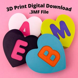 May include: Four heart-shaped 3D printed objects with letters spelling "BEAM". The letters are in contrasting colors: pink, orange, and purple. The background is a solid pink color. Text at the top reads "3D Print Digital Download .3MF File".