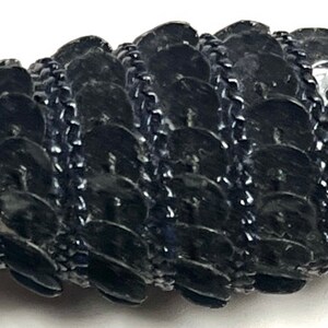Puede incluir: Borde de cadena negro con un patr&oacute;n repetitivo de peque&ntilde;as lentejuelas negras redondas y brillantes.