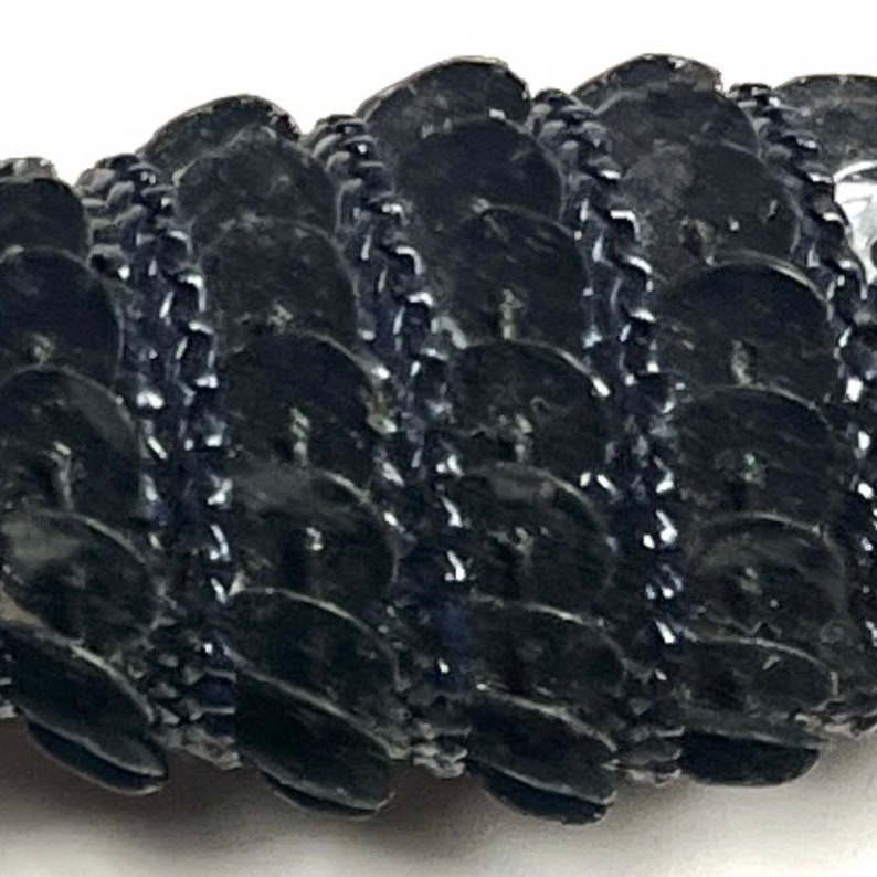 Puede incluir: Borde de cadena negro con un patr&oacute;n repetitivo de peque&ntilde;as lentejuelas negras redondas y brillantes.