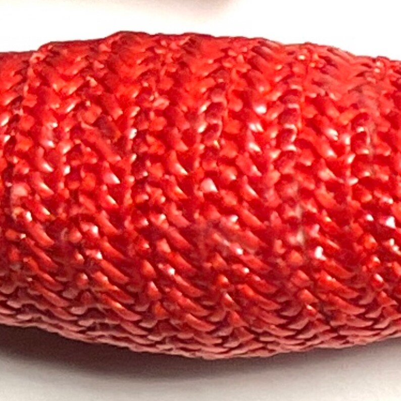 Puede incluir: Primer plano de una cuenta tejida roja con una superficie texturizada.