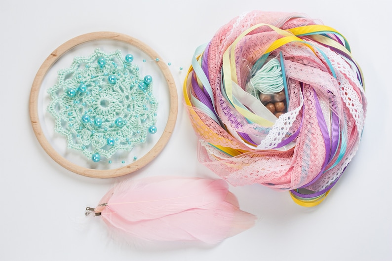 May include: A light blue crochet dreamcatcher with turquoise beads, pink feathers, and a pile of colorful ribbons and lace.