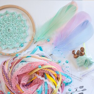 May include: A dream catcher kit with a light green crocheted circle, pastel feathers, pink and yellow ribbons, turquoise beads, and brown wooden beads.