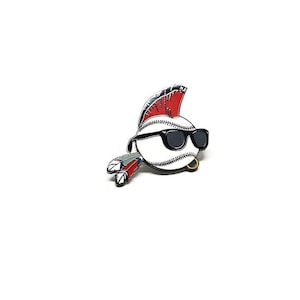 May include: A baseball-themed pin featuring a baseball with a mohawk, sunglasses, and feathers. The pin is white with black stitching, a red and silver mohawk, black sunglasses, and red, green, and blue feathers.
