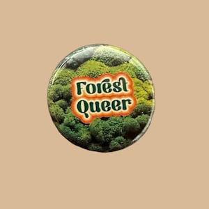 May include: A green and orange button with the text "Forest Queer" on a background of green moss.