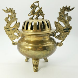 May include: A gold brass incense burner with dragon handles and a dragon finial. The burner has a round body with three legs and a perforated top.