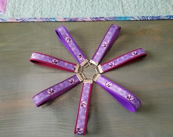 May include: Six purple and burgundy keychains with a butterfly pattern. The keychains are arranged in a star shape on a wooden surface.