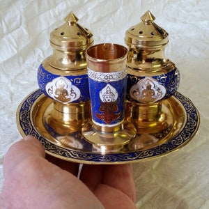 May include: Three gold and blue decorative containers with intricate designs and figures. The containers are on a gold tray with a blue and gold border.
