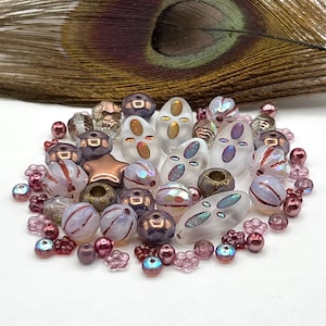 May include: A collection of assorted beads in shades of mauve, bronze, and frosted white. The assortment includes round, faceted, star-shaped, and oval-shaped beads with iridescent finishes, metallic accents, and floral-shaped spacer beads.