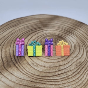 May include: Four small wooden gift boxes with glitter and ribbon details. The boxes are in shades of purple, green, pink, and orange.
