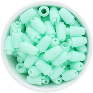 May include: A collection of mint green cord locks in a white bowl. The cord locks are cylindrical with a tapered end and a slotted base. The bowl is round and white, creating a contrast with the pastel green cord locks.