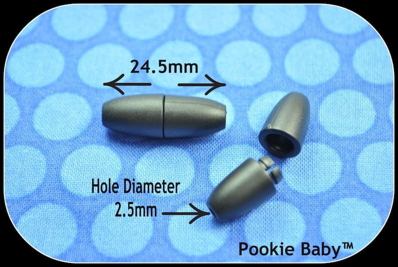 May include: Dark gray magnetic clasp with a 24.5mm length and a 2.5mm hole diameter. The clasp is shown in three pieces, with one fully assembled and two disassembled. The background is a blue fabric with white polka dots. The brand name "Pookie Baby" is visible.