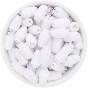 May include: A close-up shot of a white bowl filled with numerous white plastic cord locks. The cord locks are cylindrical with a rounded top and a hole for the cord. Some have a slotted design.