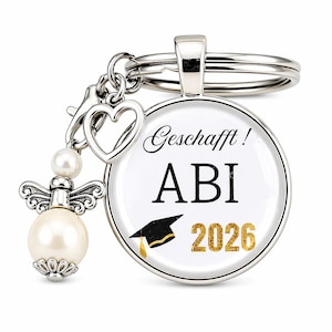 May include: Silver-toned keychain with a round pendant featuring the text "Geschafft! ABI 2026" and a graduation cap graphic. The keychain includes a heart charm and a decorative angel with a pearl.