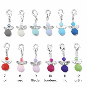 May include: A collection of twelve angel charms in various colors, each with a silver-tone clasp and wings. The charms feature a colored bead body and a smaller bead head. Colors include gray, white, blue, red, pink, purple, and green.