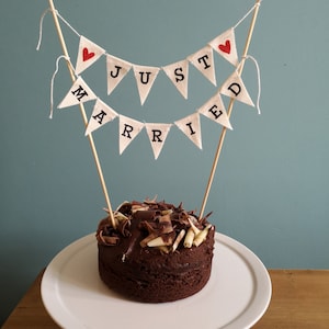 May include: A chocolate cake with white and dark chocolate shavings on top, decorated with a "Just Married" banner.