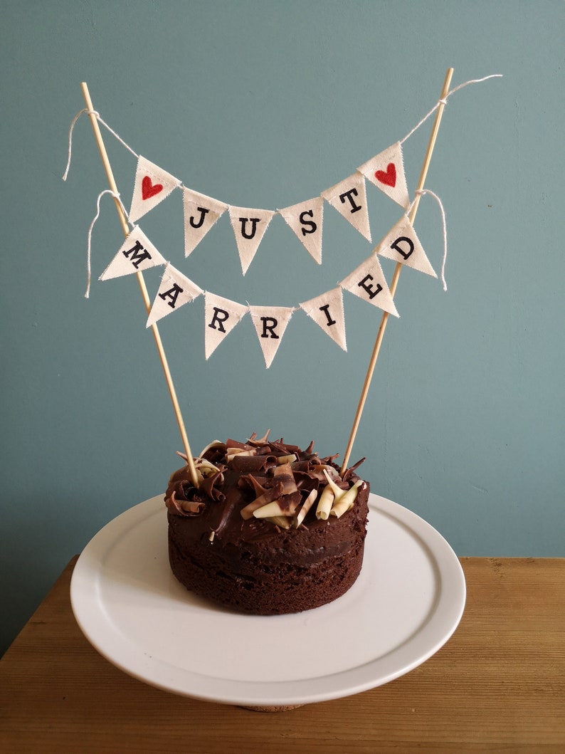 May include: A chocolate cake with white and dark chocolate shavings on top, decorated with a "Just Married" banner.