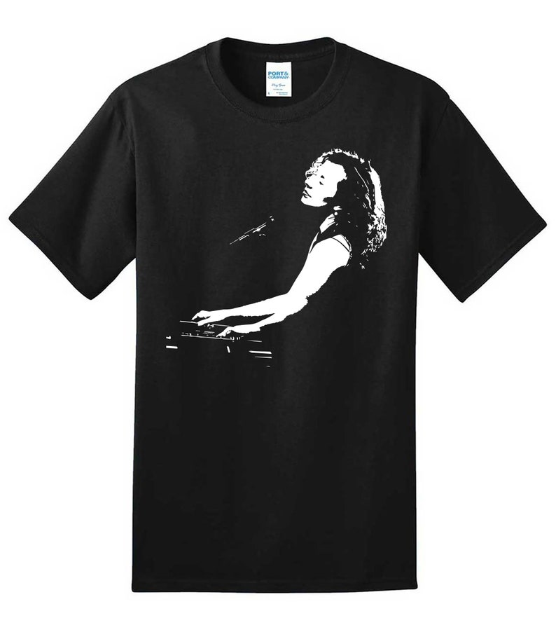 May include: Black t-shirt with a white silhouette of a person playing a keyboard.