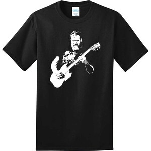 May include: Black t-shirt with a white silhouette of a man playing a guitar.