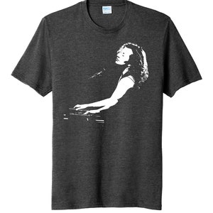 May include: A dark heather grey t-shirt with a white silhouette of a person playing a keyboard.