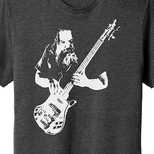 May include: A black and white illustration of a musician playing a bass guitar. The musician has a long beard and is wearing a t-shirt.