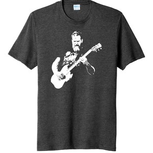 May include: A dark heather grey t-shirt with a white silhouette of a man playing a guitar.