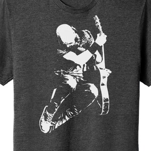 Puede incluir: Una camiseta gris oscuro con una silueta blanca de una persona tocando la guitarra.