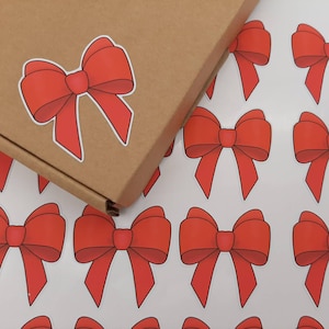 May include: A sheet of white paper with multiple red bow stickers. The bows are arranged in a repeating pattern.