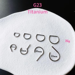 May include: A collection of titanium body jewelry, including D-shaped rings and hinged rings, in various sizes. The image displays the text "G23 Titanium" and "16g", with measurements in millimeters: 6mm, 8mm, 10mm, and 12mm.
