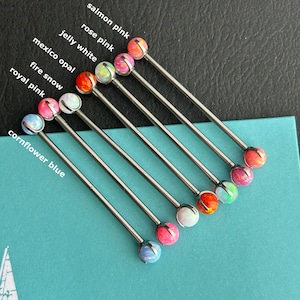 Peut inclure: Une sélection de barres industrielles avec des extrémités sphériques colorées. Les couleurs comprennent le rose saumon, le rose, le blanc gélifié, l'opale mexicaine, la neige de feu, le rose royal et le bleu bleuet. Le texte sur l'image indique les noms des couleurs. Les barres sont disposées sur une surface turquoise.