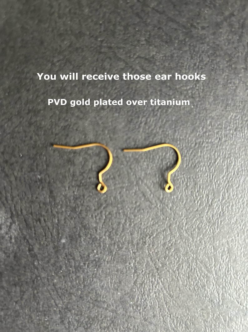 May include: Two gold-colored ear hooks with a PVD gold plated finish over titanium. The text above the hooks reads: You will receive those ear hooks PVD gold plated over titanium. These jewelry components feature a curved wire design.