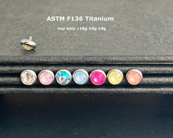 Könnte beinhalten: Sieben verschiedene farbige Edelstein-Körper-Schmuckstücke aus Titan. Die Edelsteine sind klar, rosa, blau, hellblau, rosa, gelb und rosa. Der Schmuck ist mit "ASTM F136 Titanium top only / 18g 16g 14g" gekennzeichnet.