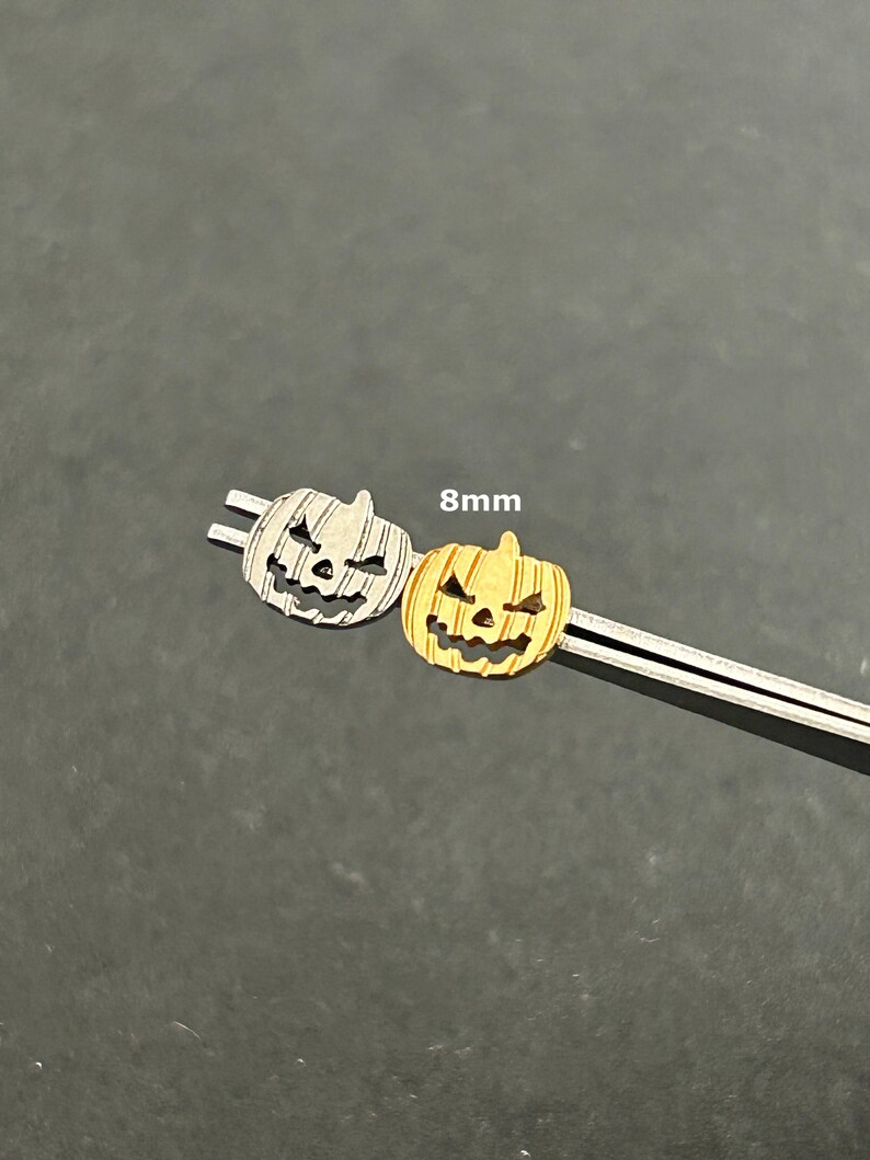 Puede incluir: Dos abalorios de calabaza de 8 mm, uno plateado y otro dorado, con una cara de calabaza tallada.