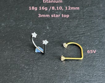 May include: Two pieces of body jewelry on a dark surface. One is a curved barbell with star-shaped ends. The other is a gold-colored, U-shaped piece with star-shaped ends. Text reads: titanium, 18g 16g /8,10, 12mm, 3mm star top, and 65V.
