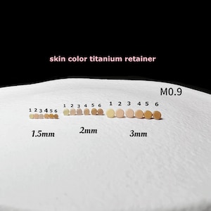 Könnte beinhalten: Eine Auswahl an hautfarbenen Titan-Retainern in verschiedenen Größen: 1,5 mm, 2 mm und 3 mm. Jede Größe enthält sechs Retainer, nummeriert von 1 bis 6. Der Text "skin color titanium retainer" ist sichtbar.