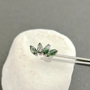 May include: A silver body jewellery piece with five green gemstone accents in a curved shape.