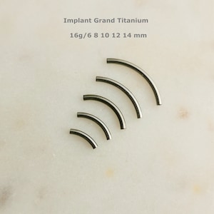 May include: Five different sizes of curved, implant grade titanium body jewellery, ranging from 6mm to 14mm in length. The text "Implant Grand Titanium 16g/6 8 10 12 14 mm" is printed above the jewellery.