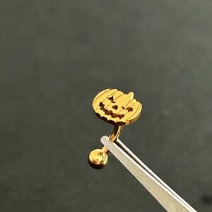 Puede incluir: Anillo de ombligo de color dorado en forma de calabaza con una peque&ntilde;a bola en el extremo.