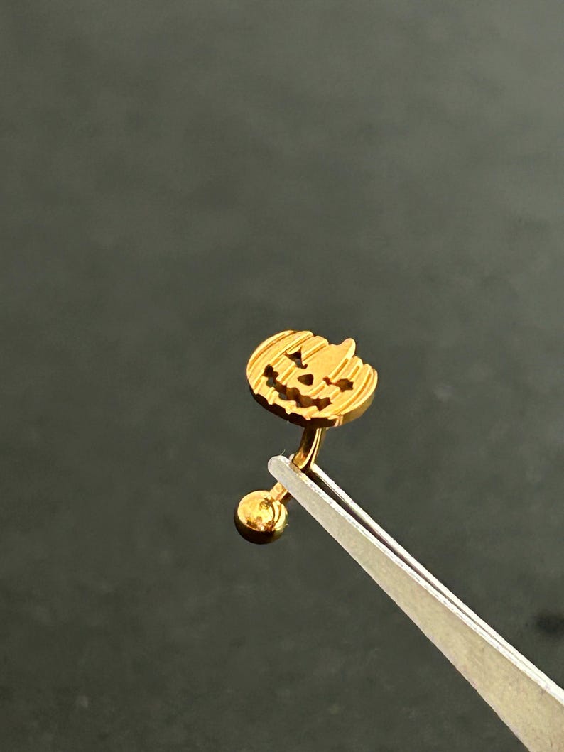 Puede incluir: Anillo de ombligo de color dorado en forma de calabaza con una peque&ntilde;a bola en el extremo.