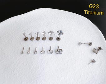 Pode incluir: Uma coleção de piercings labret de titânio G23 com gemas transparentes de corte redondo em vários tamanhos. As peças de joalharia estão dispostas em duas filas, com peças adicionais à direita, exibindo hastes metálicas e bases planas.