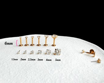 Pode incluir: Um conjunto de joias para o corpo de titânio de 6 mm com pedras preciosas transparentes de vários tamanhos, que vão de 1,5 mm a 5 mm. As joias são exibidas em uma superfície branca. G23 Titânio.