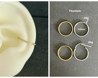 May include: Two sets of nose rings, one set is gold and the other is titanium. The gold set is 18 gauge and the titanium set is 20 gauge. Both sets are 12mm in diameter.