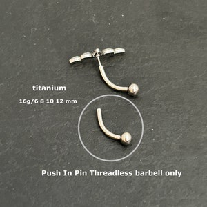 Peut inclure: Un barbell incurvé de couleur argentée avec une extrémité en forme de boule et un dessus décoratif. Le texte "titanium" et "16g/6 8 10 12 mm" sont visibles. Le texte "Push In Pin Threadless barbell only" est également présent.