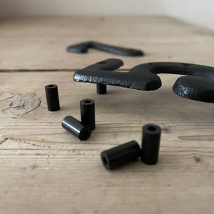 May include: Black metal house numbers with black plastic spacers. The numbers are on a wooden surface.