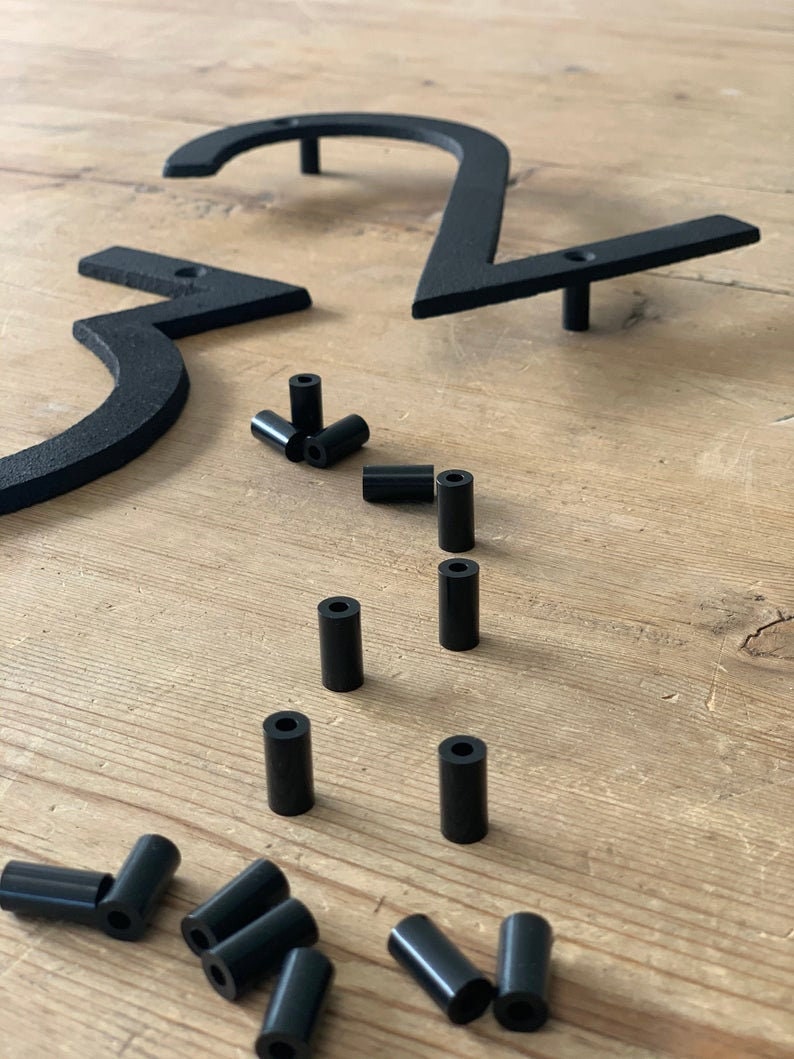 May include: Black metal house numbers, including the numbers 2 and 3, with mounting hardware. The numbers are in a modern font and are shown with several black cylindrical spacers. The numbers are designed for outdoor use.