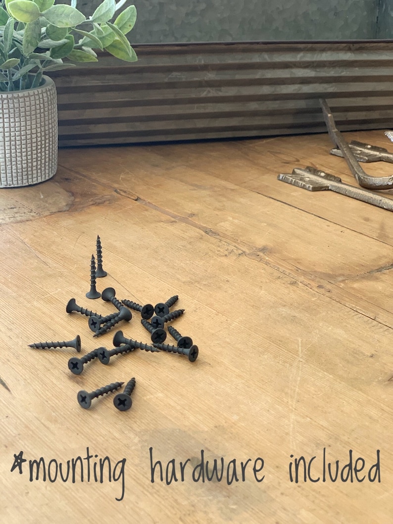 Puede incluir: Primer plano de tornillos negros sobre una superficie de madera. El texto "#mounting hardware included" est&aacute; escrito debajo de los tornillos.