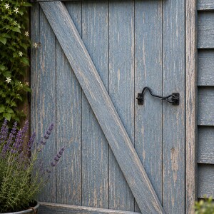 May include: A weathered blue wooden door featuring vertical planks, a diagonal brace, and a black metal cabin hook latch. The wood grain shows signs of wear with visible texture and paint distress, mounted within a matching blue siding frame.