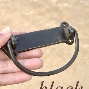 May include: Black metal drawer pull with a rectangular plate and a rounded loop handle.