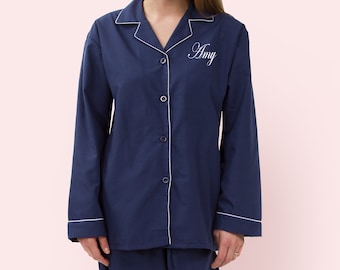 May include: A navy blue pajama set with long sleeves and pants. The top has a white button-up closure and a white embroidered name "Amy" on the chest.