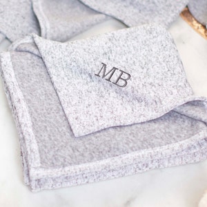 May include: A gray, soft, and cozy blanket with the initials "MB" embroidered in black thread.